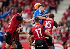 El defensa del Oviedo cabecea el balón ante dos jugadores del Mirandés.