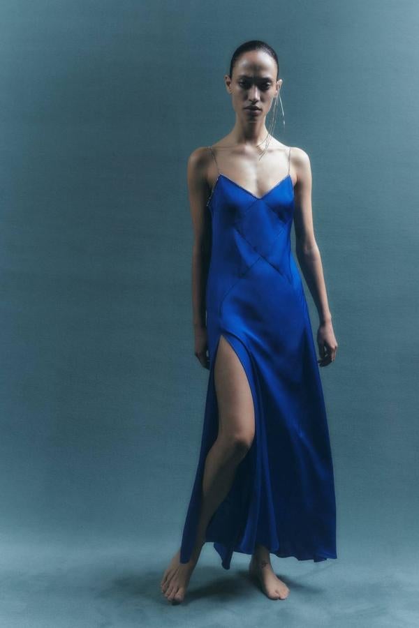 Vestido largo lencero en tejido satinado con escote de pico, abertura en el bajo y tirantes de strass, color azul, de Zara. Cómpralo por 79,95 euros.
