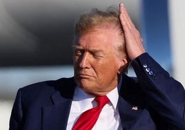 Donald Trump se arregla el pelo con su mano.
